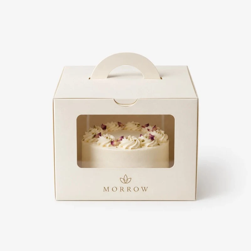 White cake box with a handle and a window showing a cake, brand Morrow