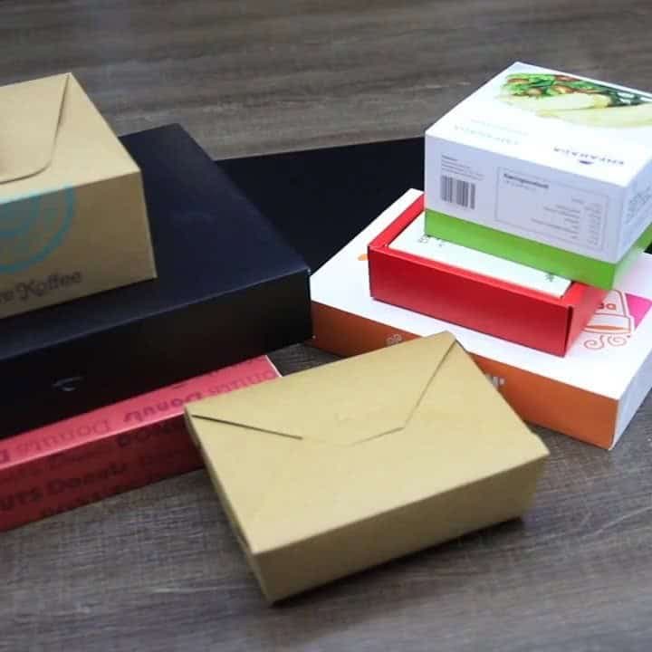 Kraft takeout box beside black, red and white printed paperboard boxes