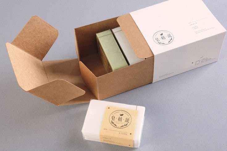 Open kraft soap box with a white sleeve holding two soap bars, and a wrapped soap bar in front