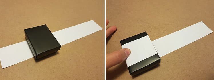 A paper sleeve being slid around a small black box